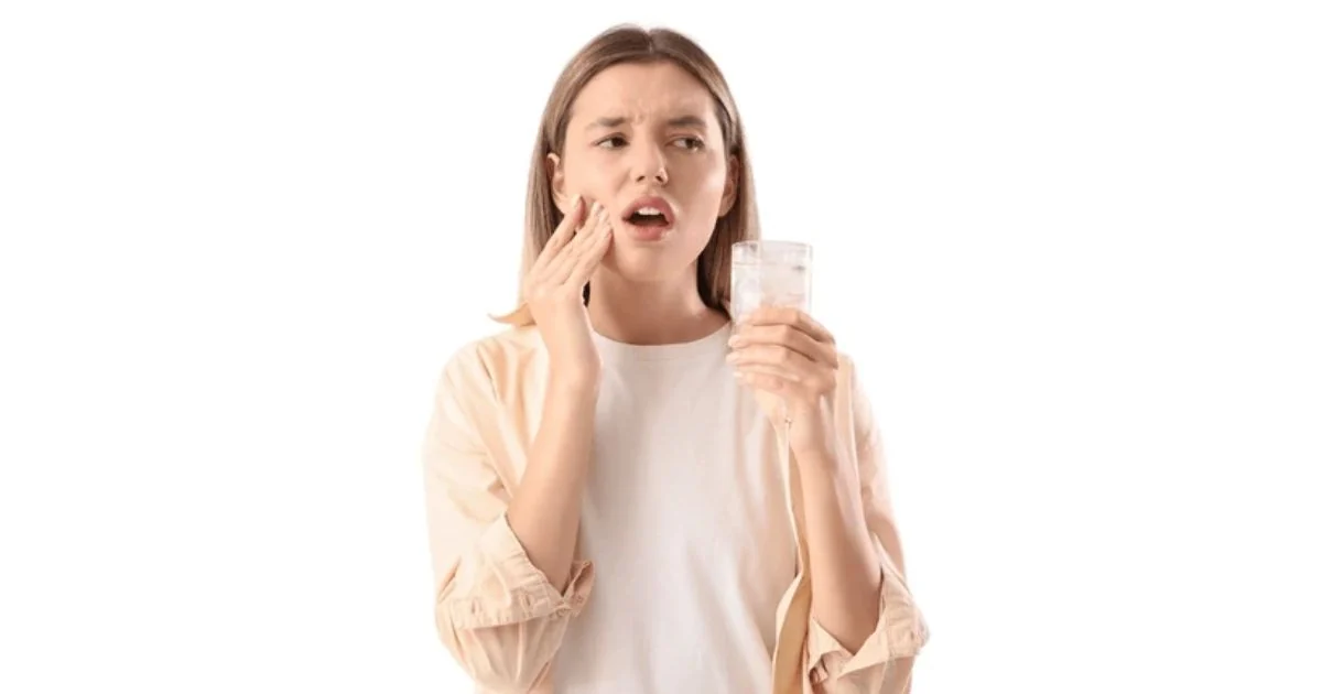 mulher com dor e sensibilidade nos dentes após tomar água gelada